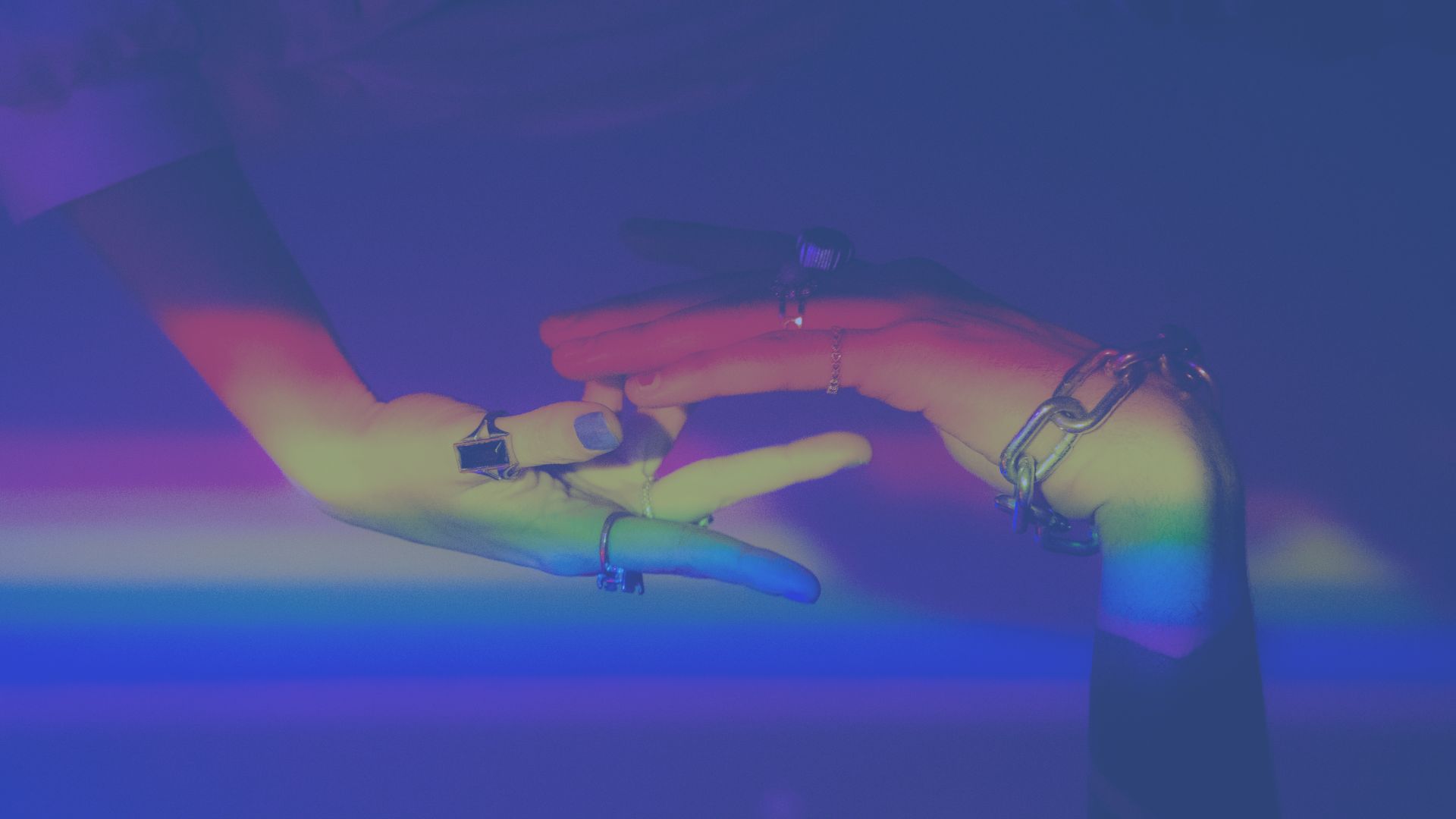 Two hands hovering over each other, one from above and one from below, fingers barely touching with rainbow light across page with blue overlay